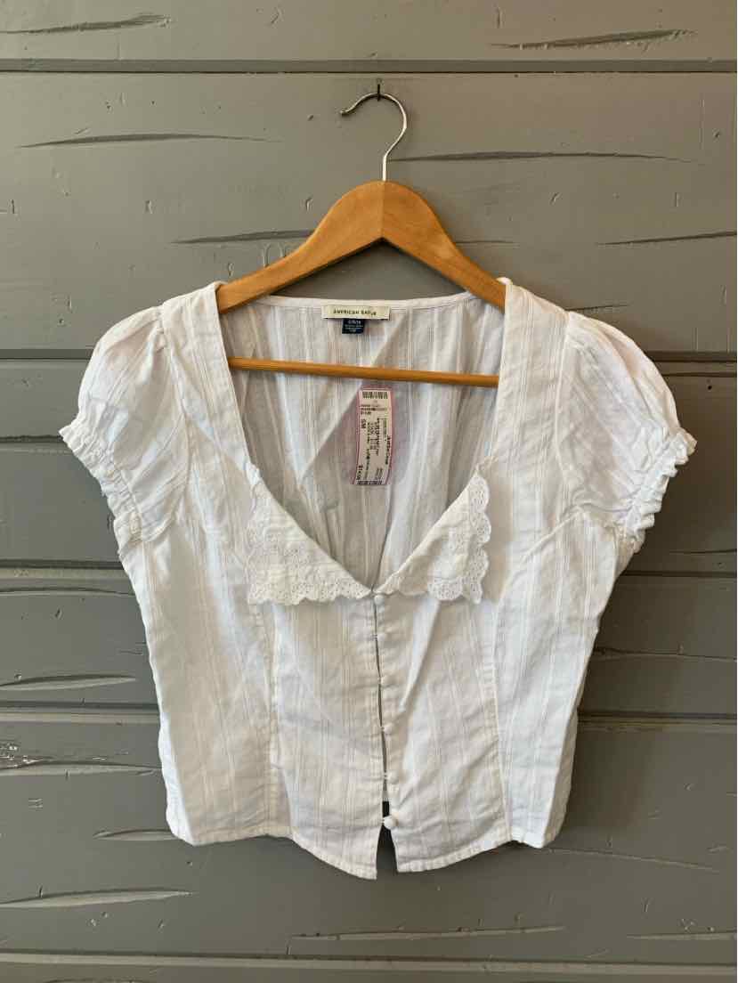 White short-sleeve blouse with deep V-neck and button-down front on wooden hanger.