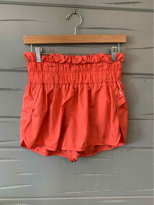 Rust-colored high-waist shorts with a gathered, ruffled waistband and loose fit, made of lightweight fabric.