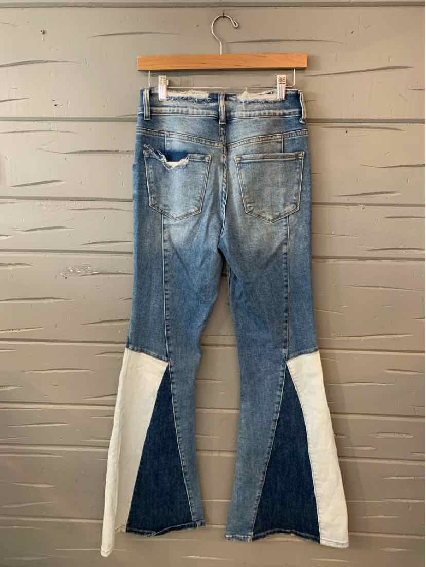 Blue denim jeans with two-tone white and dark blue triangular fabric panels on the back lower legs, distressed detailing on.