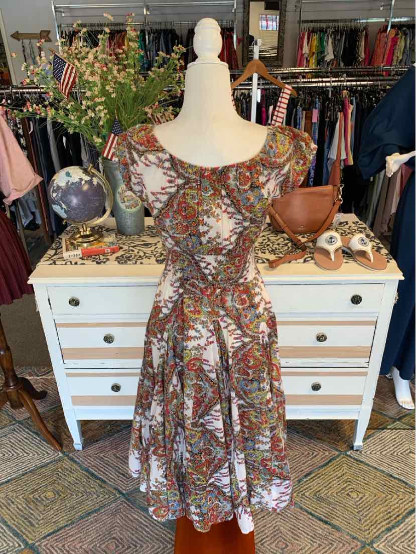 Sleeveless midi dress with fitted bodice and flared skirt, featuring multicolored paisley print on lightweight fabric.