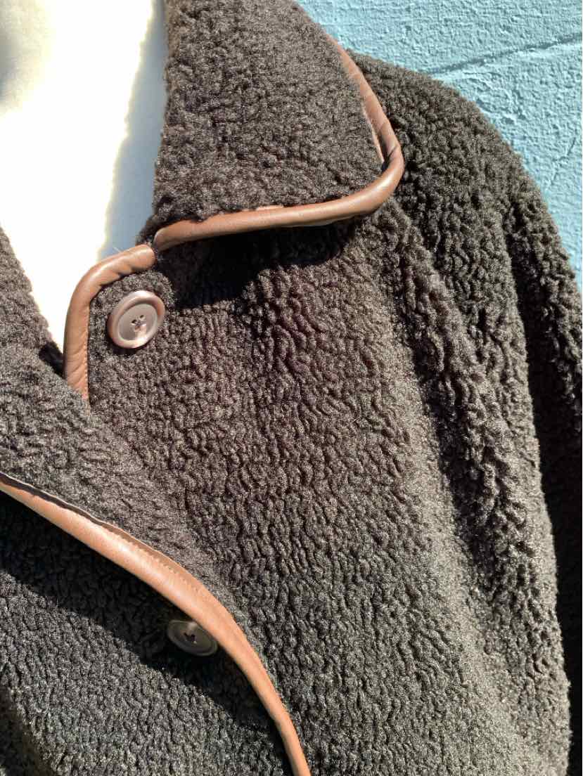 Black textured fleece jacket with brown trim, snap-button closure, and a wide collar.