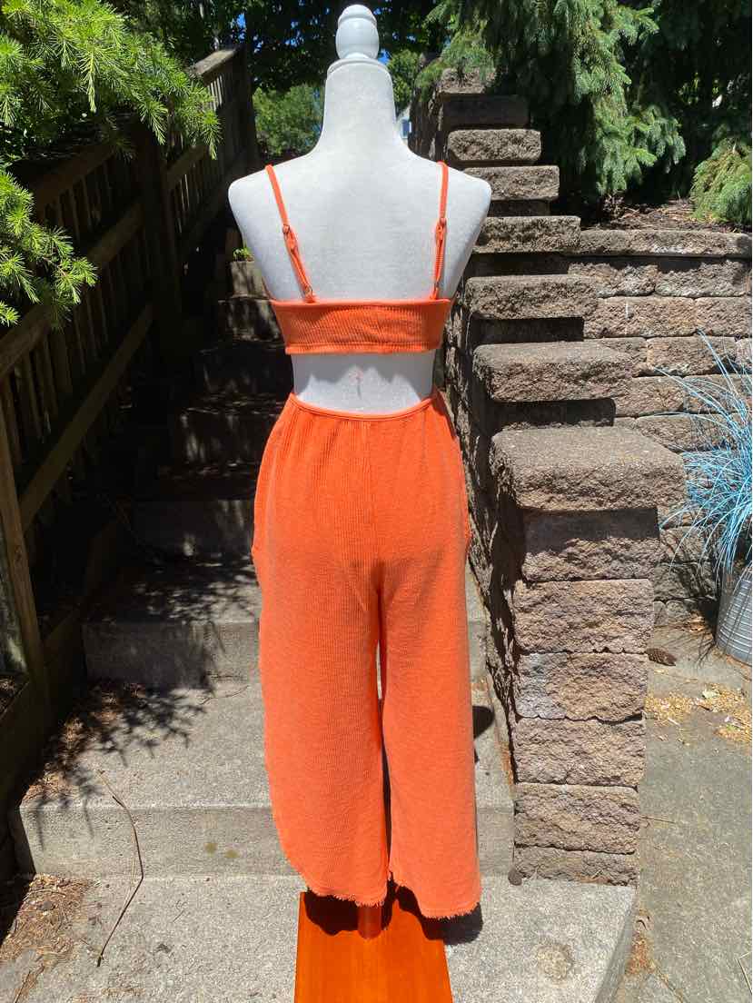 Bright orange two-piece lounge set with cropped tank top and high-waisted wide-leg pants in soft fabric.