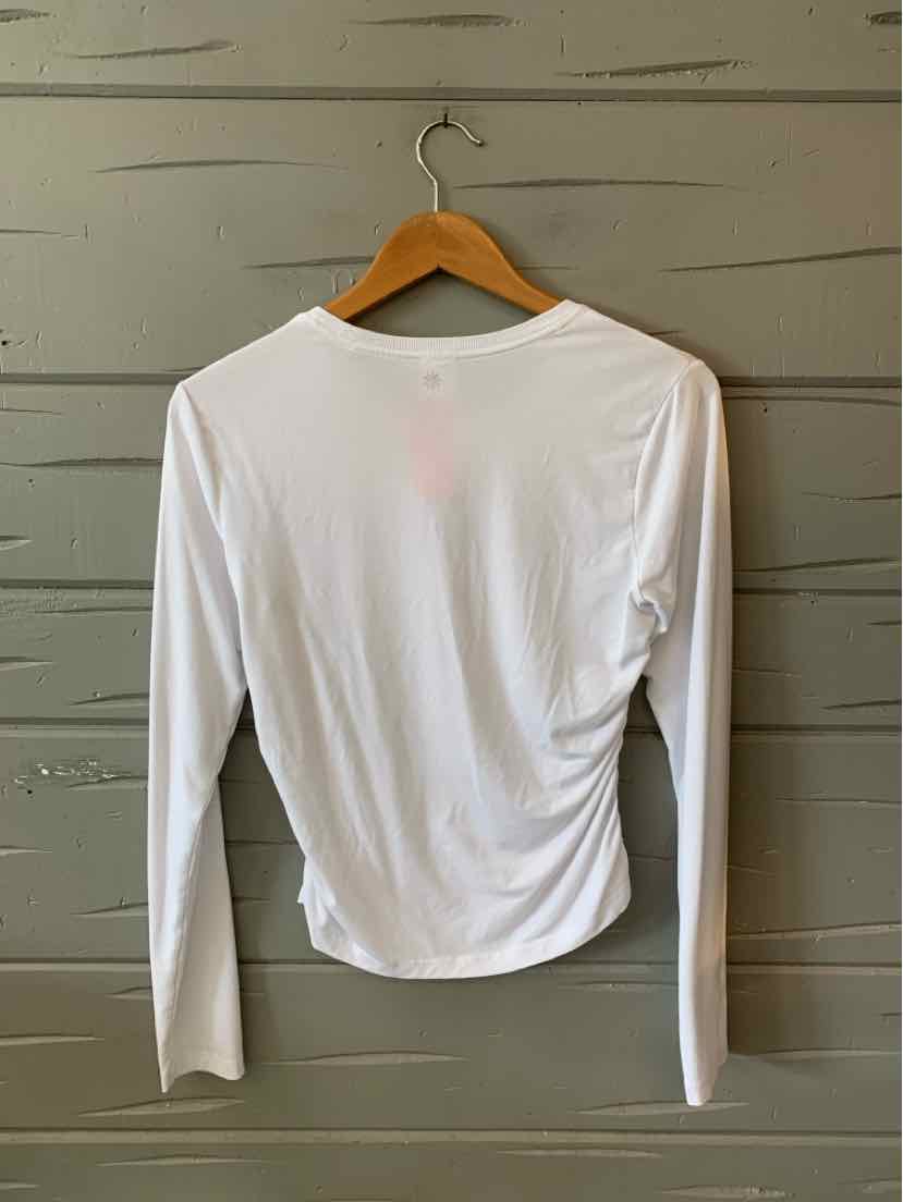 White long-sleeve fitted athletic top with crew neckline hanging on wooden hanger.