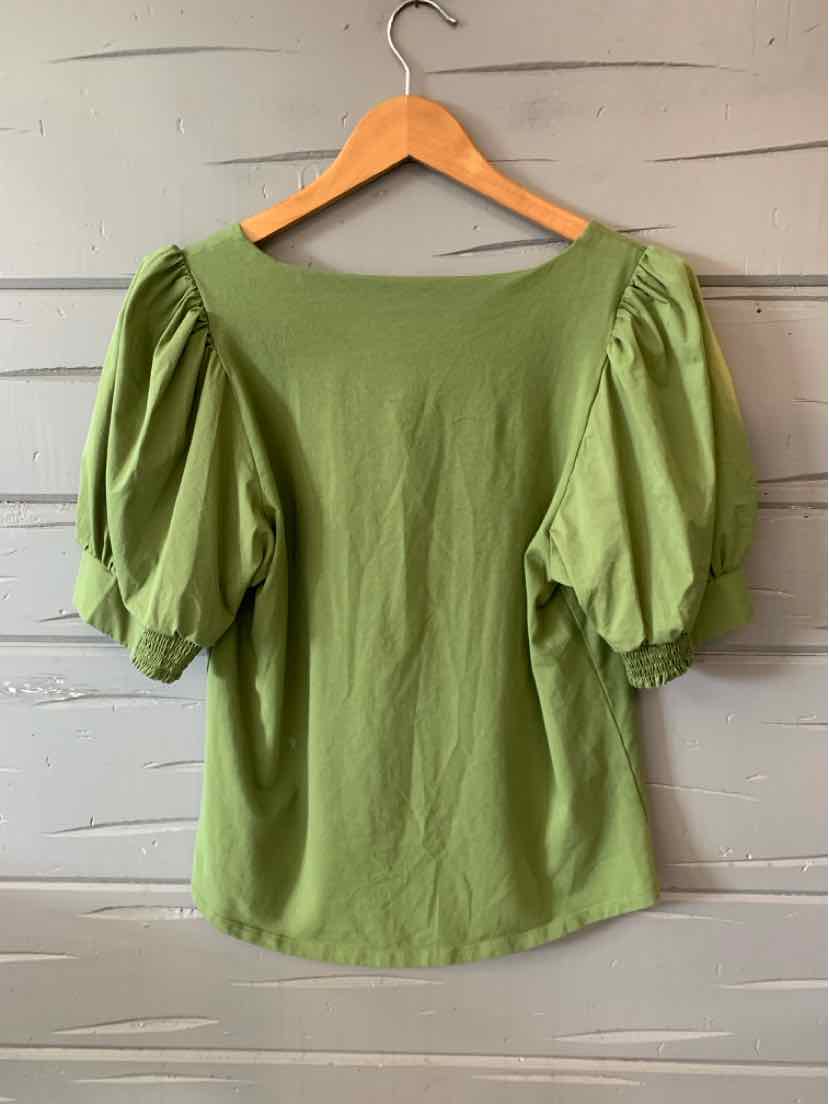 Light green blouse with puffed short sleeves and a boat neckline on a wooden hanger.