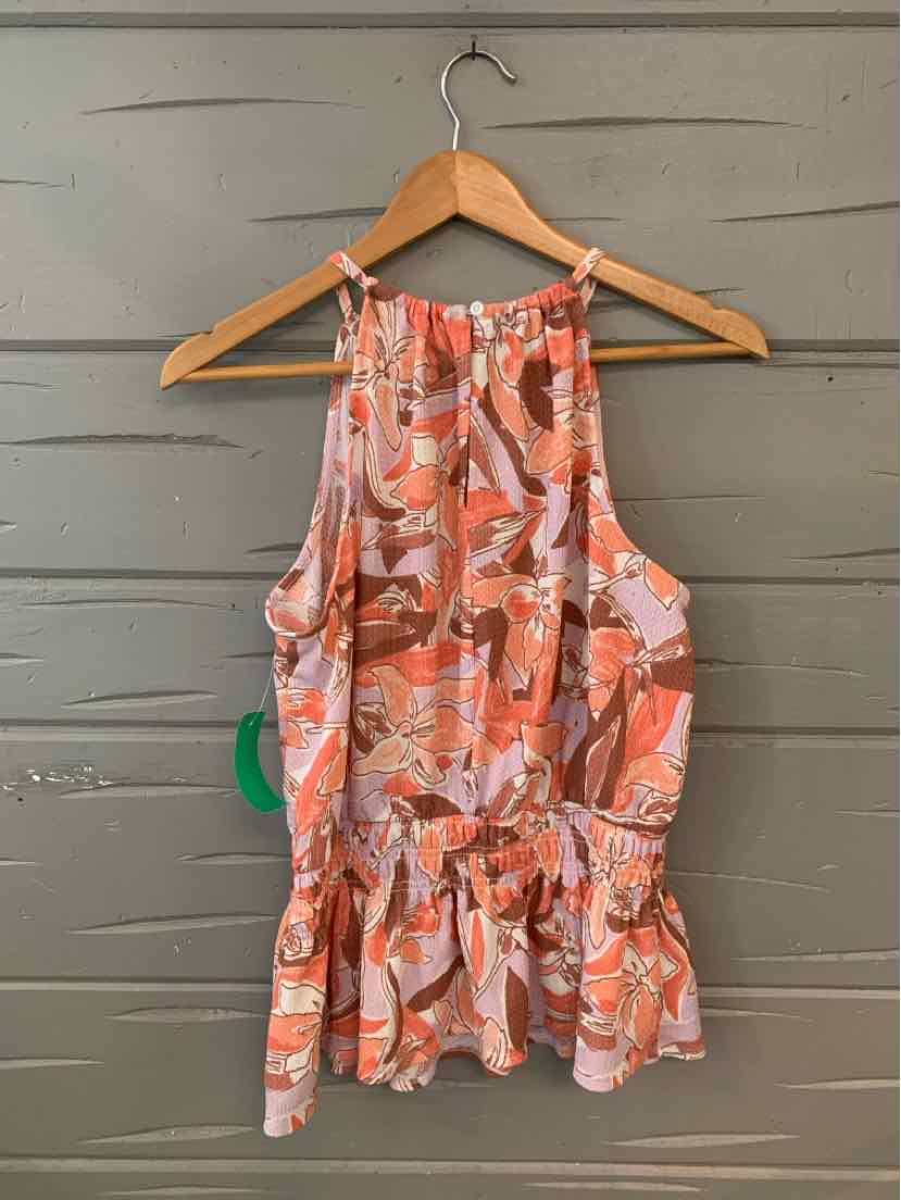 Pink sleeveless floral blouse with tie waist and ruffled hem on wooden hanger against gray wall.
