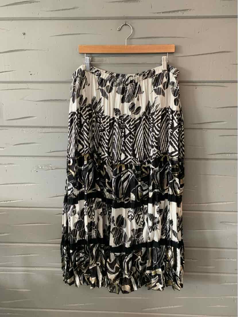 Black and white floral maxi skirt with tiered ruffles and elastic waistband hanging on wooden hanger.
