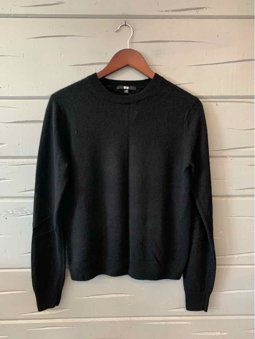 Black crewneck long-sleeve sweater with ribbed cuffs and hem hanging on wooden hanger.