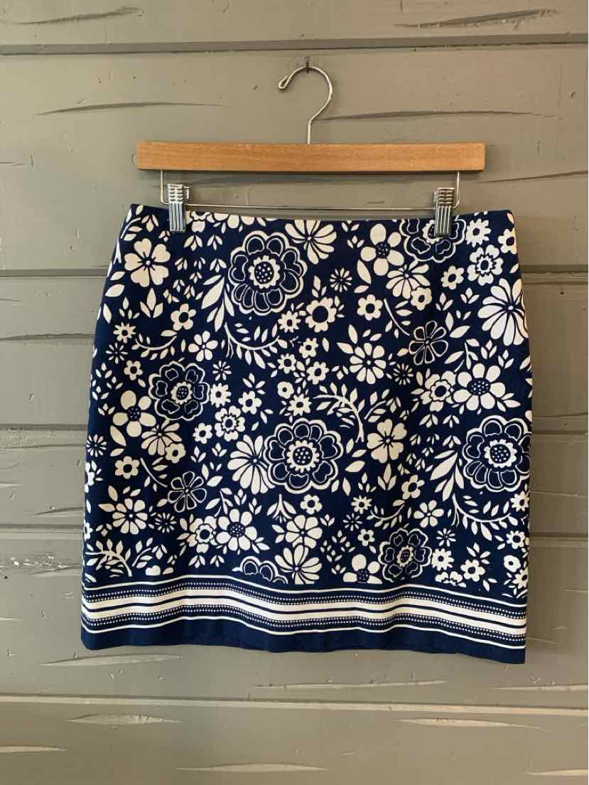 Navy blue skirt with white floral print and striped hem hanging on wooden hanger.