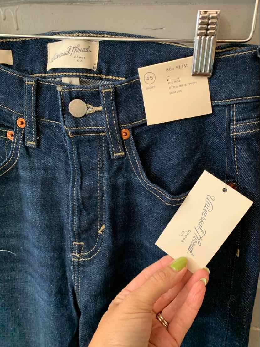 Dark blue denim jeans with a high waist, metal button closure, and front pockets, featuring white brand tags.
