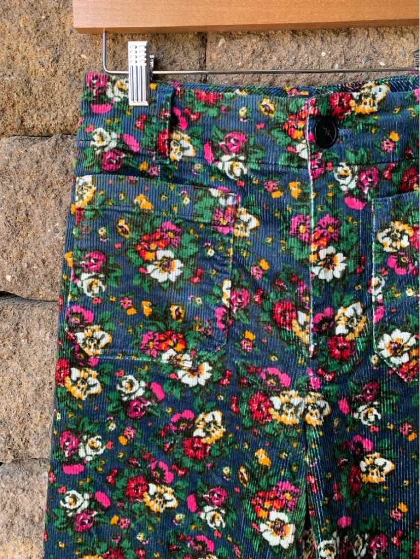 Green denim shorts with multicolored floral print and frayed hem.