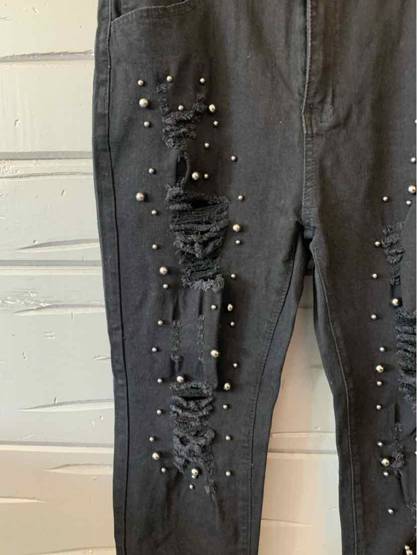 Black distressed denim jeans with ripped details and silver studs on front legs, size XL.