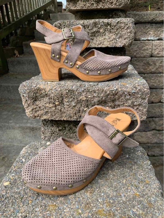 Brown perforated leather clogs with wooden block heels and adjustable ankle straps.