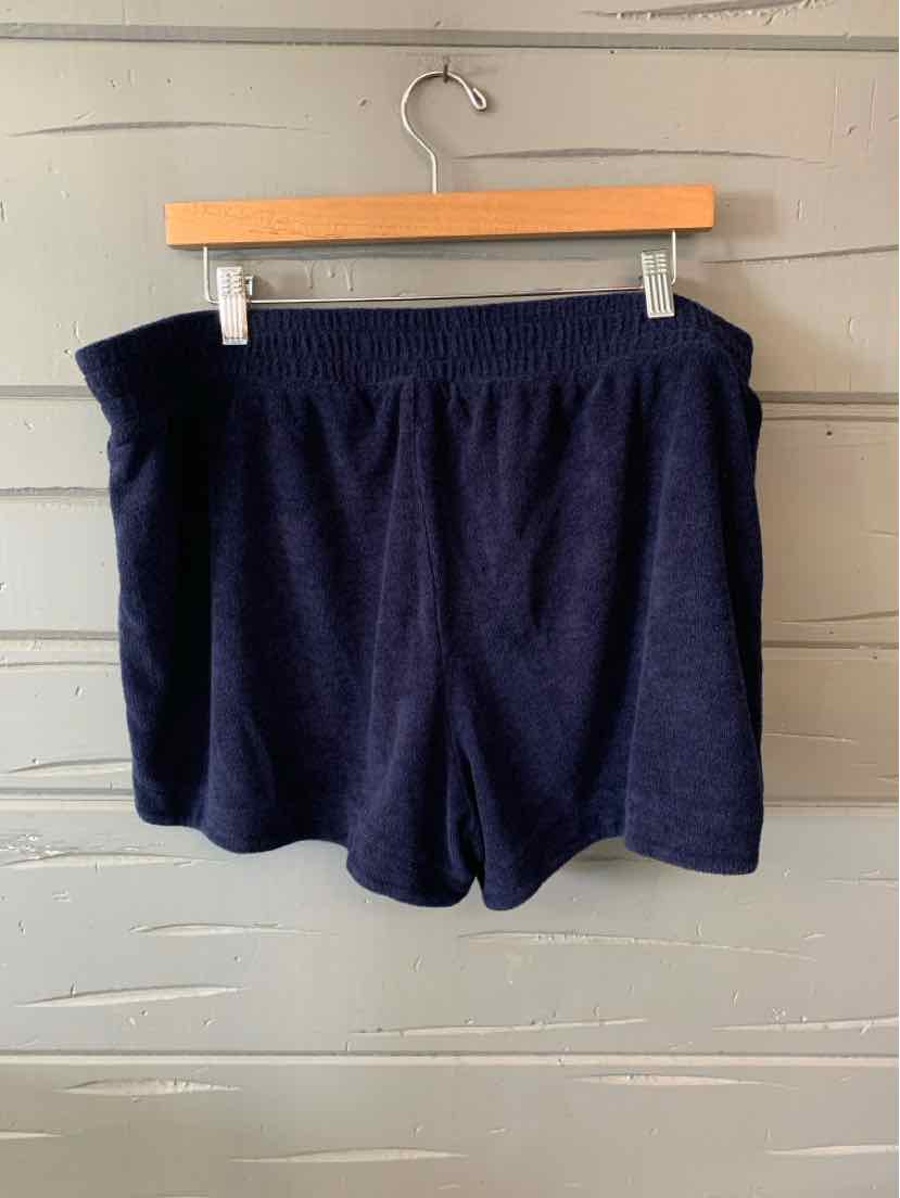 Navy blue solid knit shorts with elastic waistband hanging on wooden hanger.