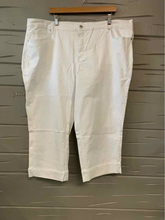White mid-length pants with front button and zipper closure hanging on wooden hanger.