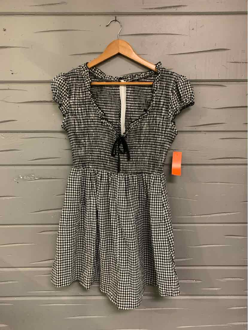 Black and white gingham short-sleeve dress with ruffled shoulders, cinched waist, and front tie detail.