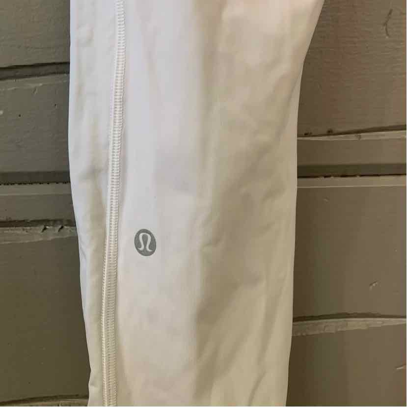 White Lululemon activewear leggings with reflective logo on lower leg.