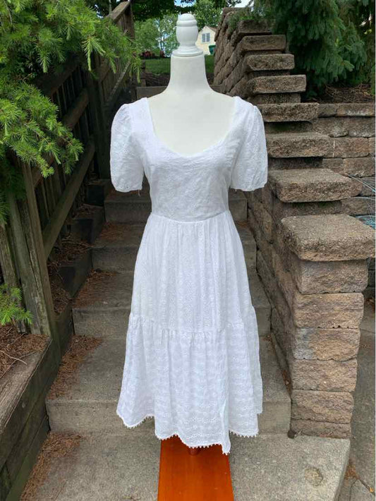 White midi dress with puff sleeves, square neckline, and tiered eyelet lace skirt.