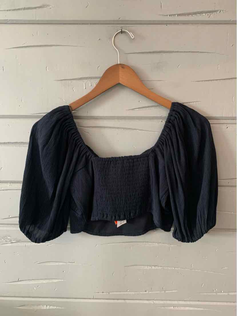 Black cropped blouse with smocked square neckline and puffed three-quarter sleeves on wooden hanger.
