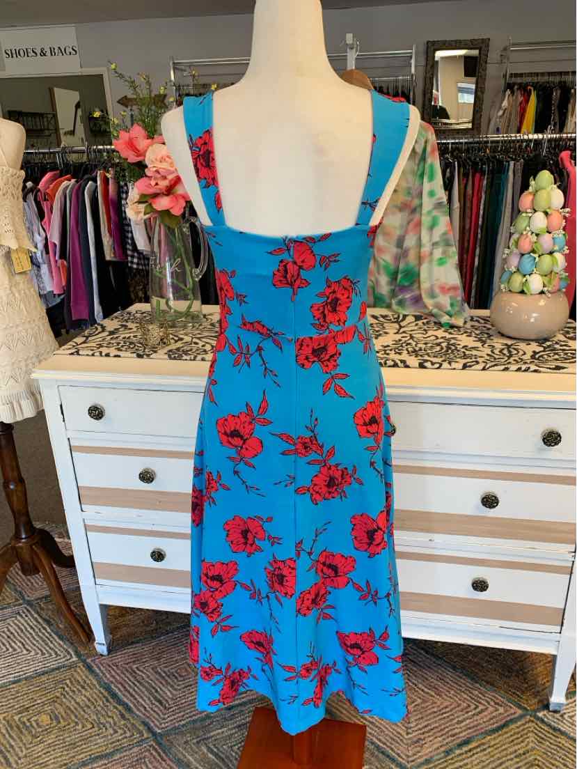 Blue floral midi dress with red roses and thin shoulder straps on mannequin.