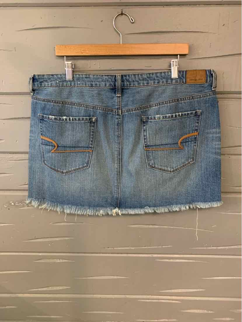 Light blue denim mini skirt with frayed hem and back patch pockets on wooden hanger.