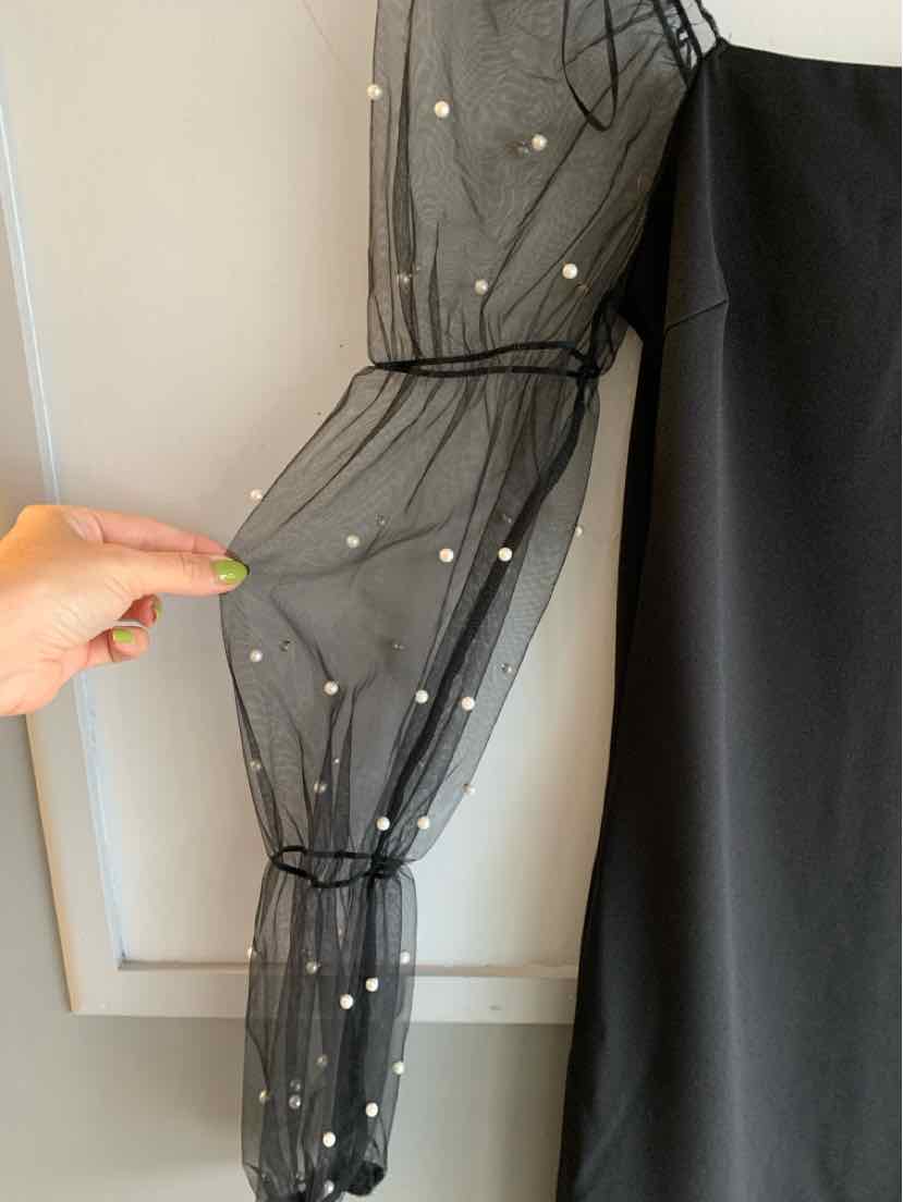 Black sheer sleeve with white polka dots, cinched with elastic at wrist and upper arm, attached to black fabric garment.