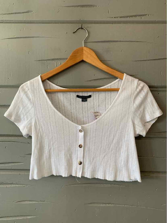 White ribbed cropped top with short sleeves, scoop neckline, and front button closure.