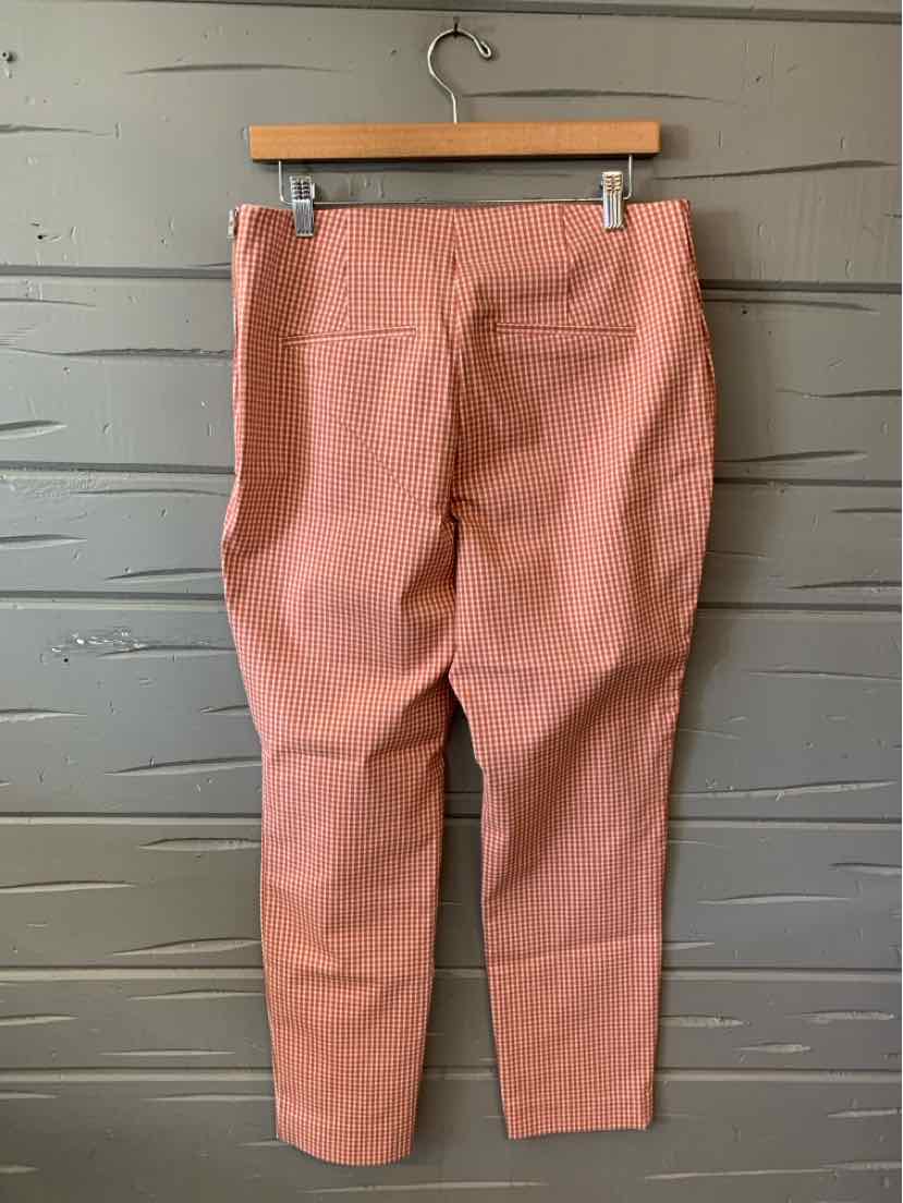 Rust-colored pants in size 12 with a slim fit and back patch pockets hanging on a wooden hanger.
