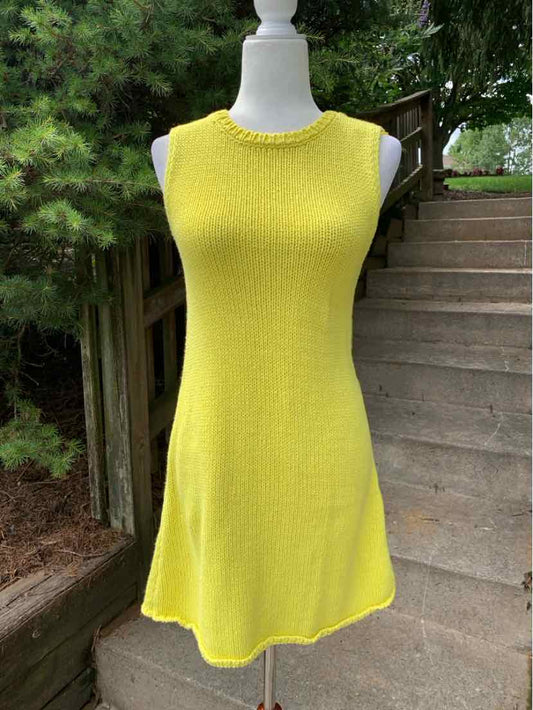 Sleeveless yellow knit dress with crew neckline and flared hem on mannequin outdoors.