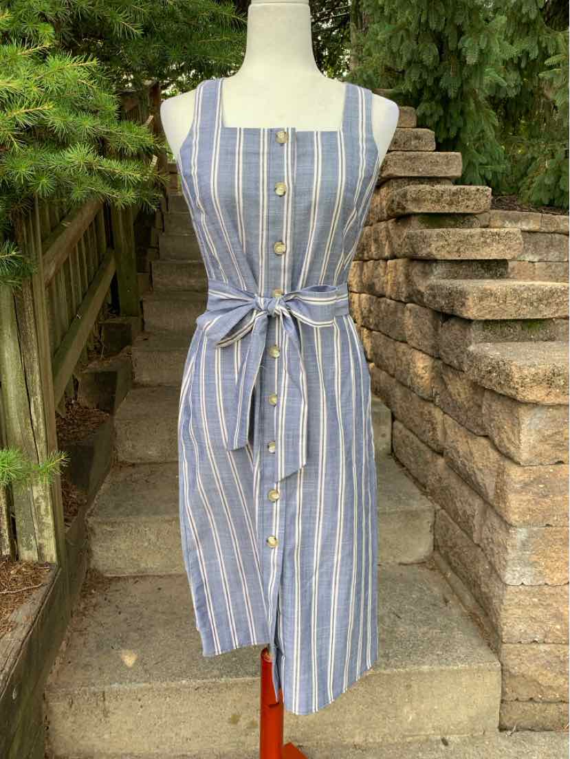 Sleeveless blue midi dress with white vertical stripes, square neckline, front buttons, and waist tie belt.