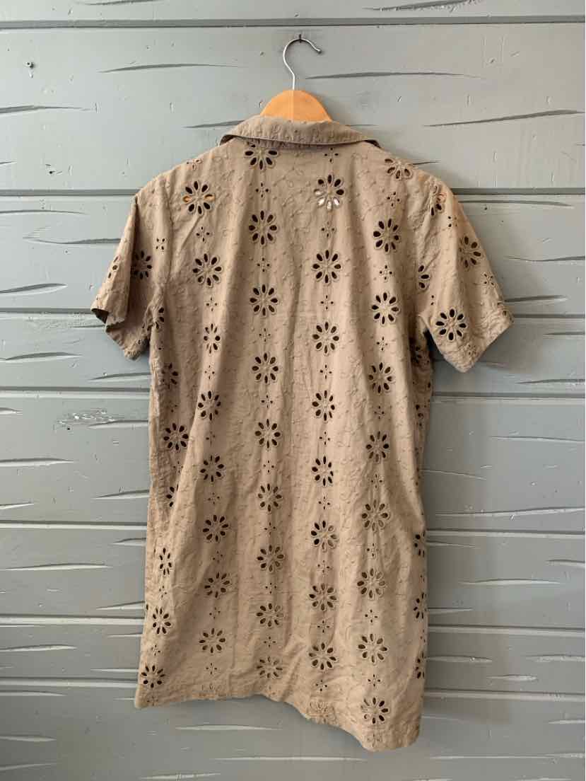 Beige short-sleeve dress with floral eyelet patterns and a collar hanging on a wooden hanger.