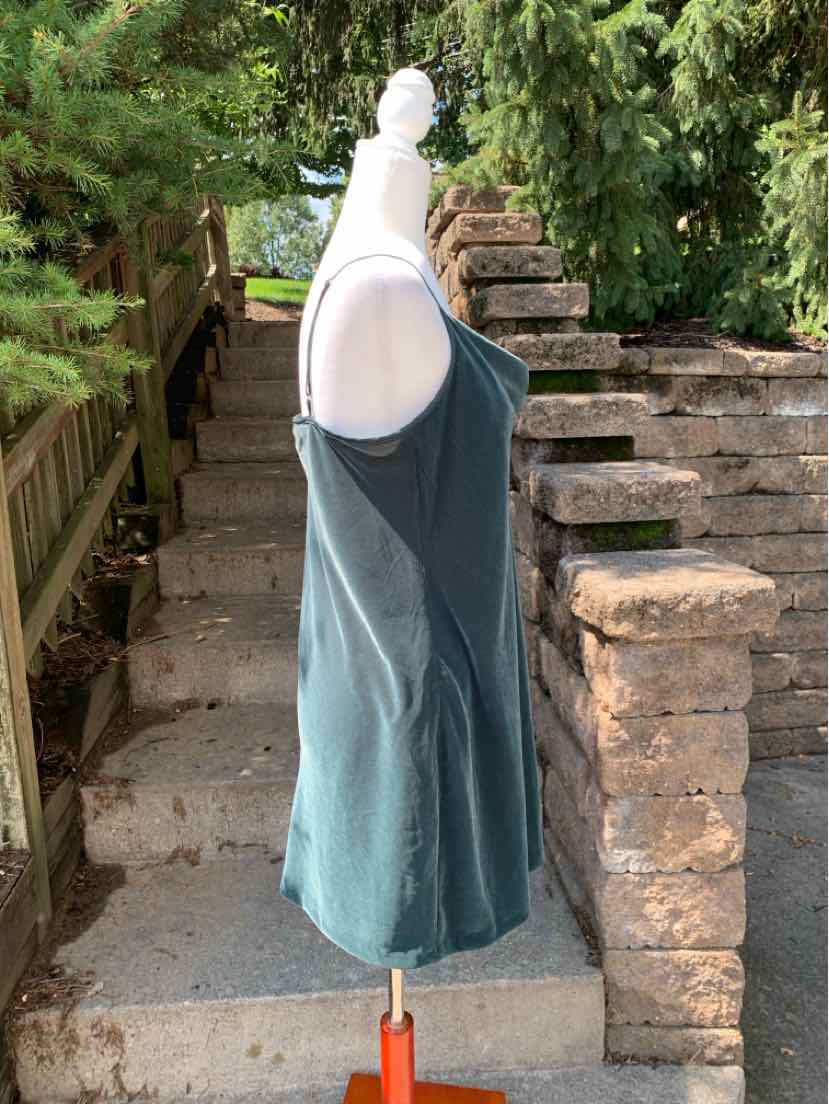 Sleeveless green tank top with scoop neckline and relaxed fit on white mannequin outdoors.