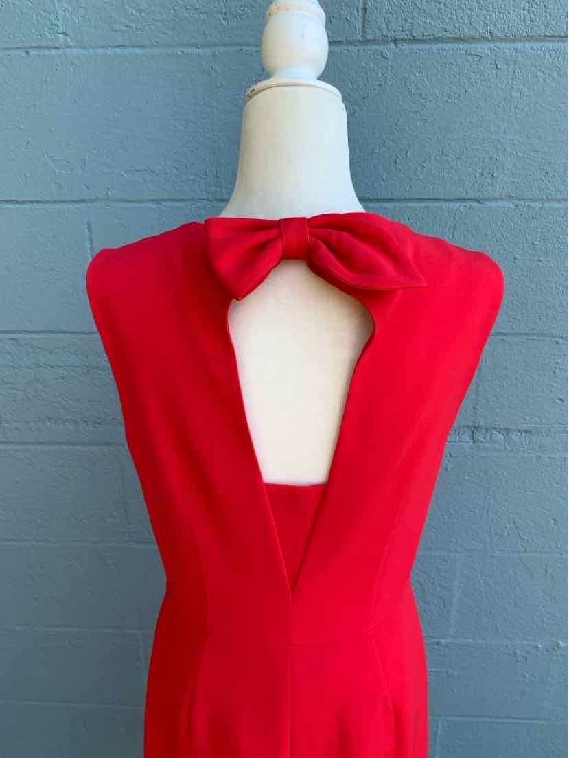 Red sleeveless dress with deep V-back and large bow detail at neckline on mannequin.