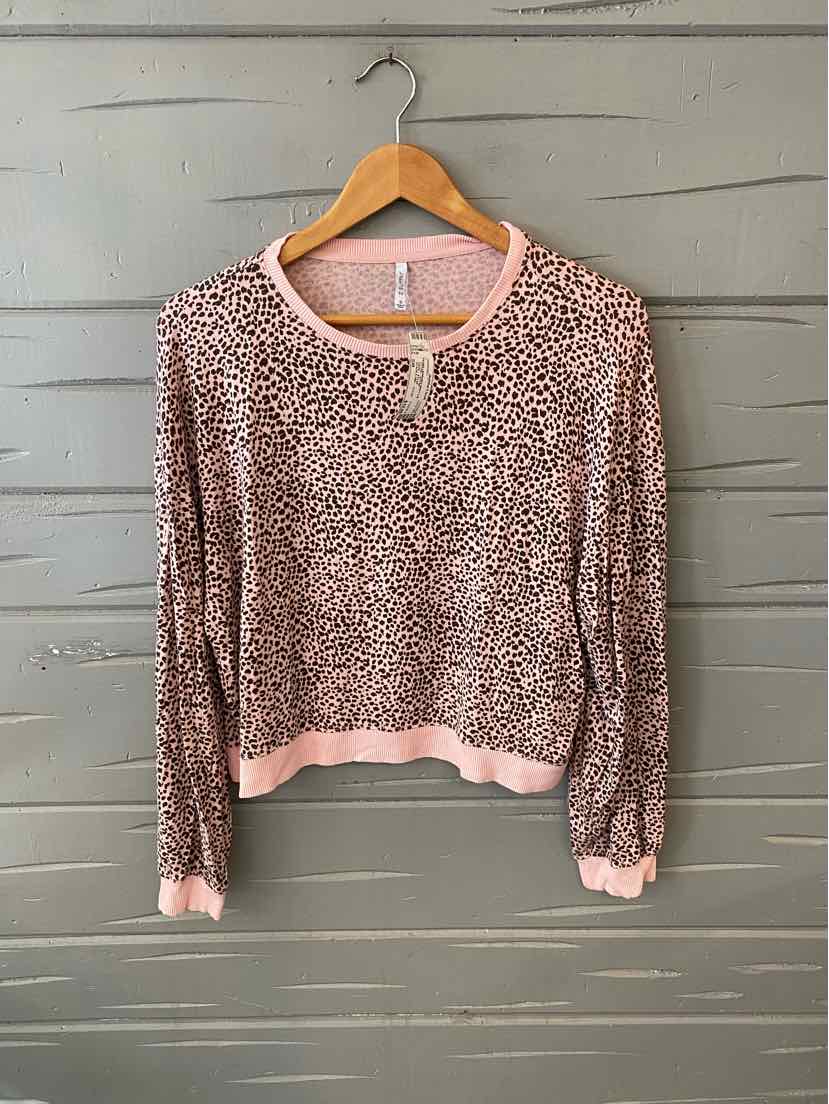 Pink leopard print long-sleeve shirt with ribbed cuffs and hem on wooden hanger.