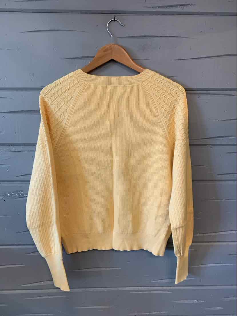 Cream-colored knit sweater with textured shoulder panels and ribbed cuffs and hem.