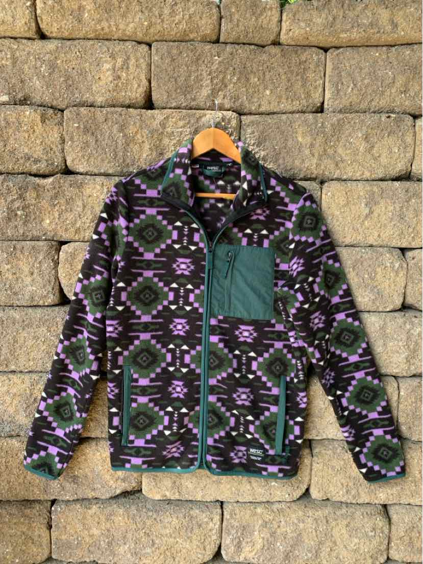 Black and purple aztec-patterned zip-up jacket with green chest pocket and collar trim.