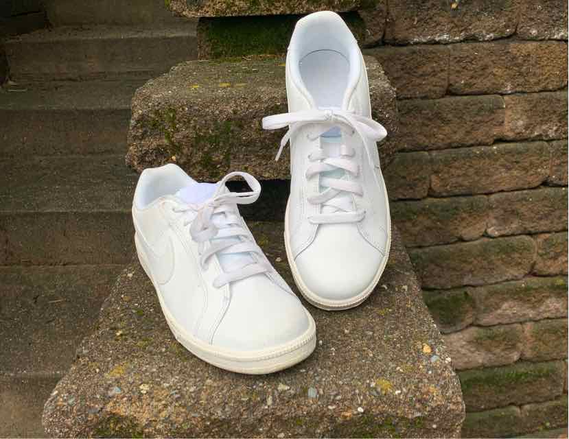 White low-top Nike sneakers with lace-up design and smooth leather upper, size 9.