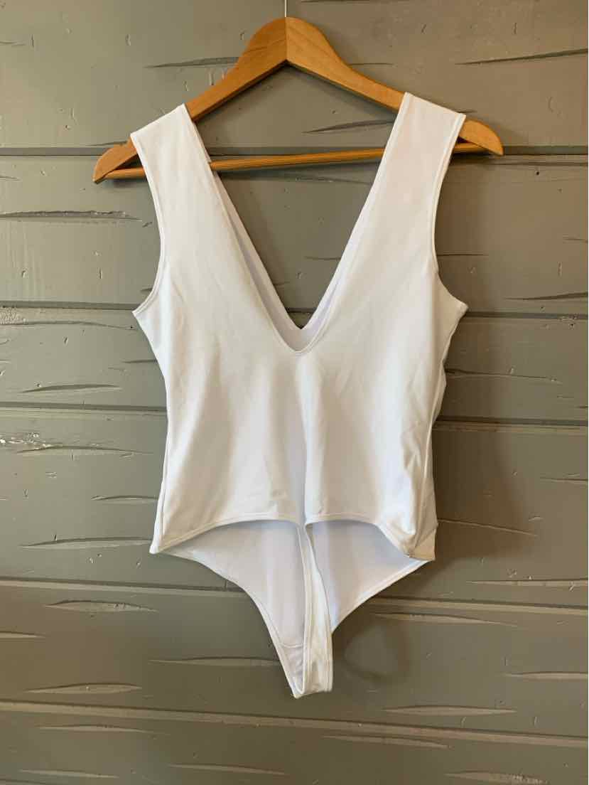 White sleeveless bodysuit with deep V-neck and high-cut leg openings on wooden hanger.