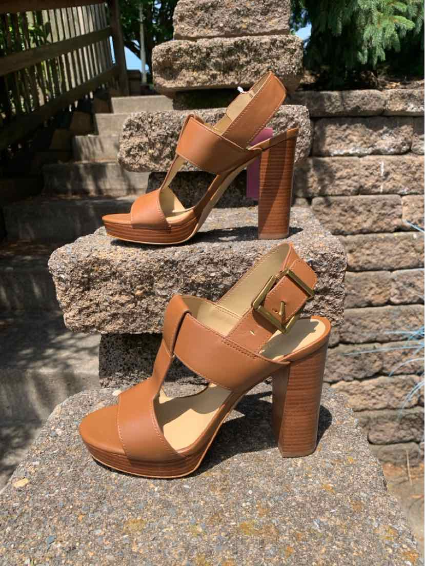 Tan leather high-heeled sandal with chunky heel, open toe, and buckle ankle strap.