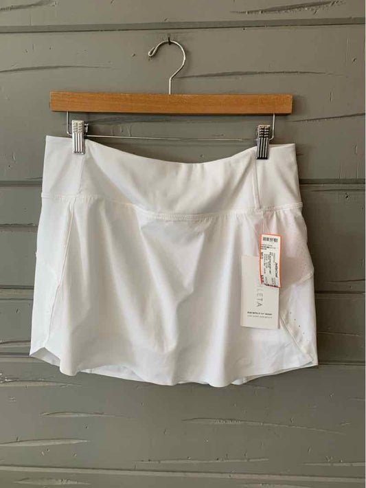 White athletic skirt with slight flare, smooth fabric, mid-rise waist, and attached tag hanging on wooden hanger against.