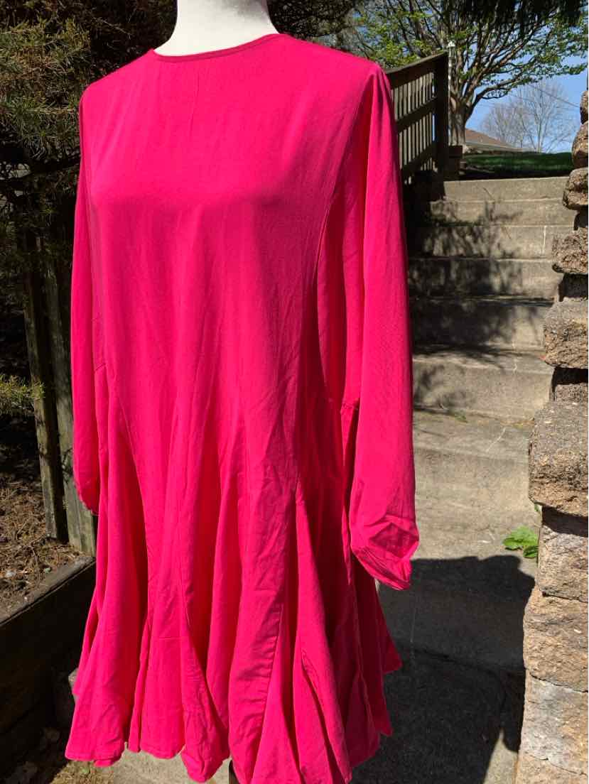 Bright pink long-sleeve dress with relaxed fit and round neckline on mannequin outdoors.