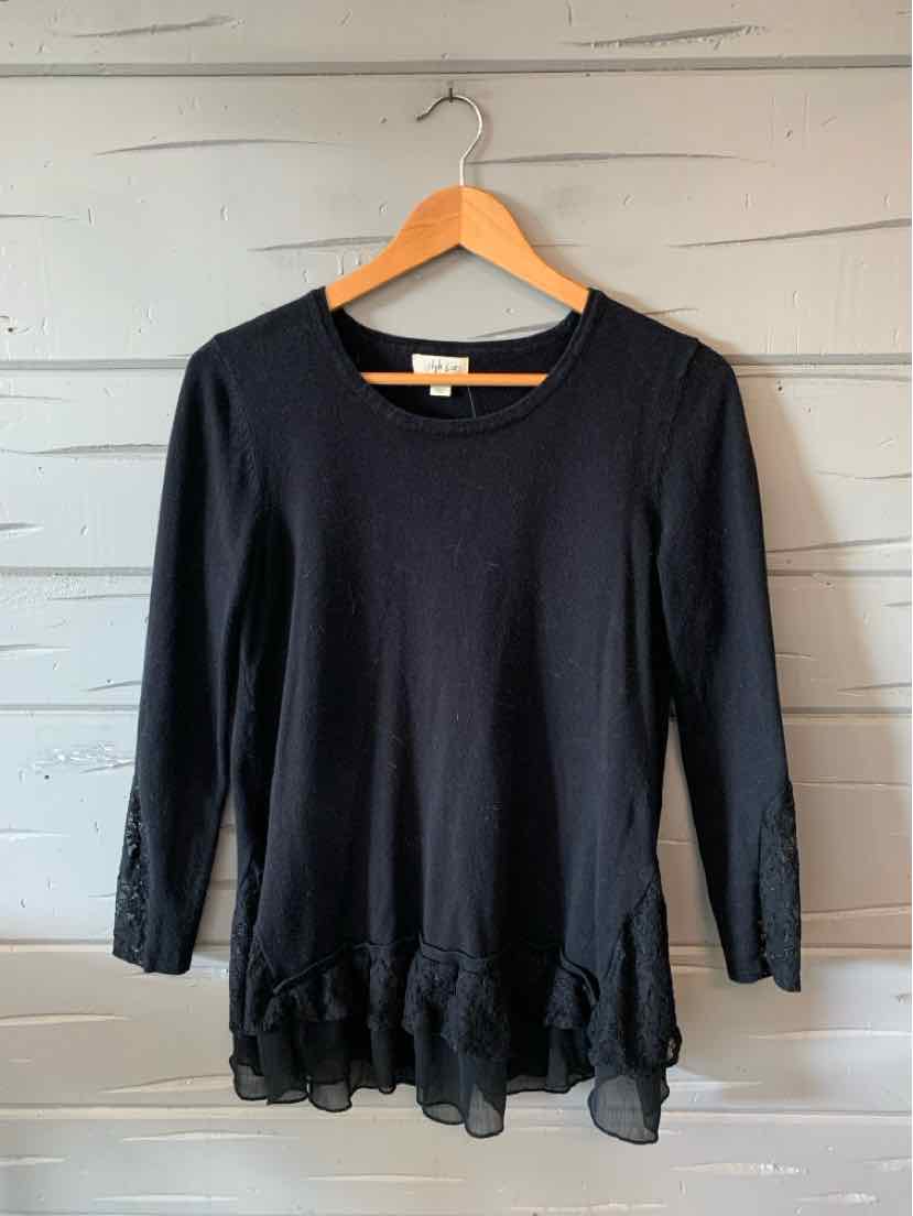 Black long-sleeve blouse with round neckline and ruffled sheer hem detail.