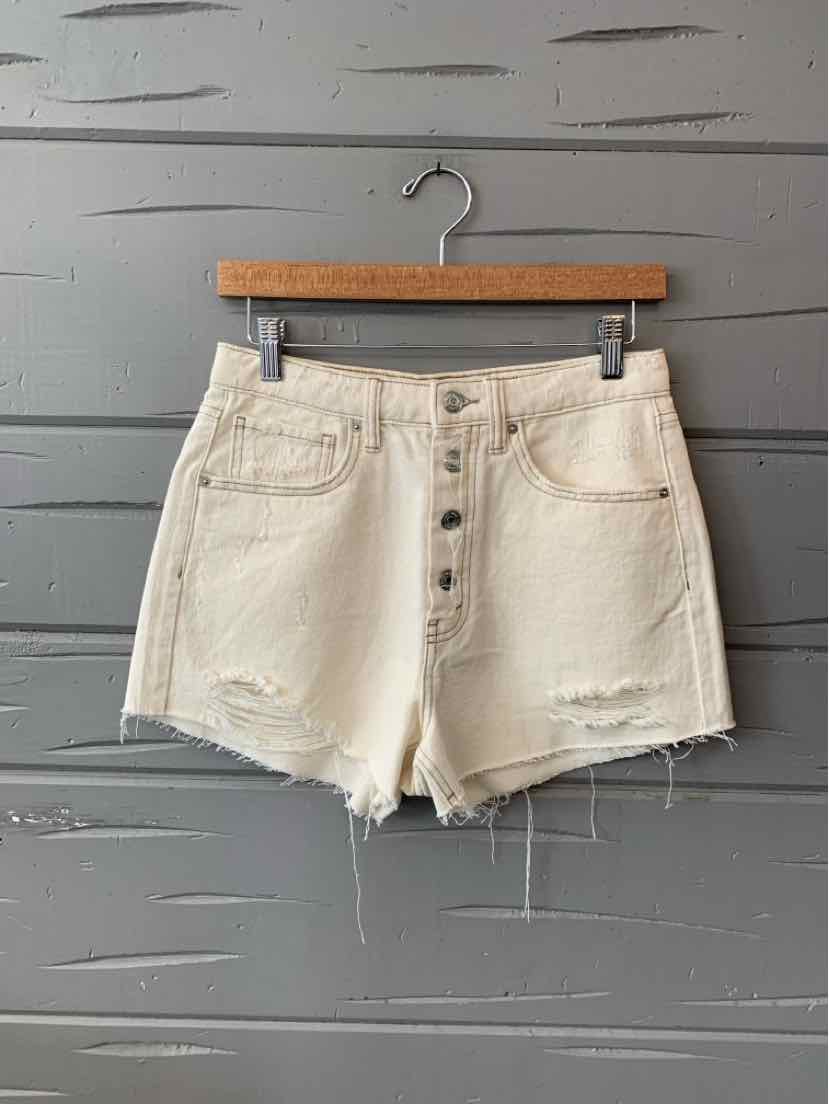 High-waisted cream denim shorts with front button closure and distressed hem detailing.