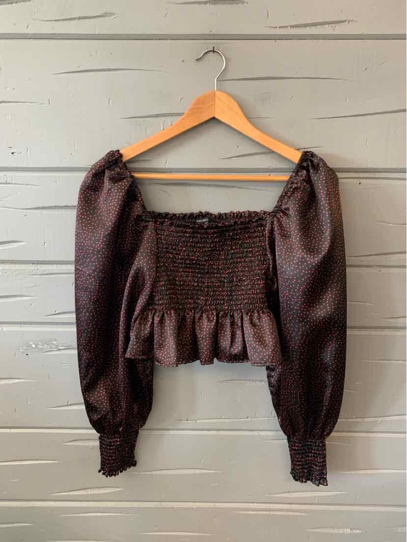 Black cropped blouse with long puffed sleeves, smocked bodice, and ruffled hem.