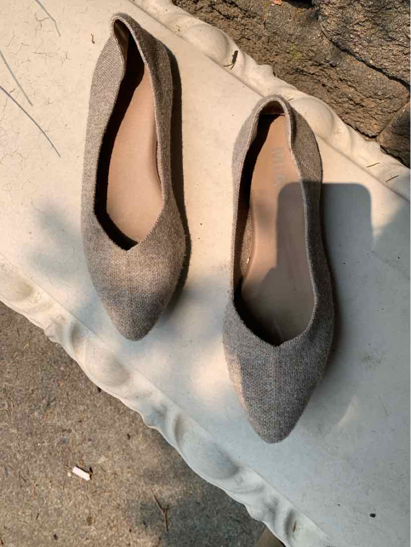 Pair of beige pointed-toe flats with a smooth fabric texture and low-cut sides, size 10.
