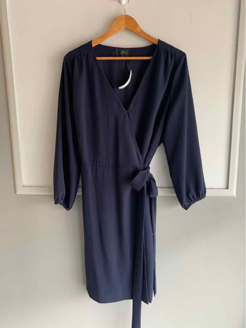Navy blue wrap dress with 3/4 sleeves and side tie belt hanging on wooden hanger.