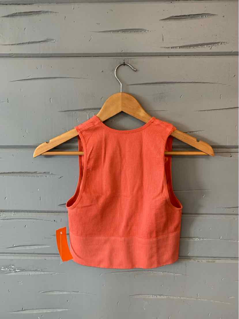 Coral cropped tank top with wide shoulder straps and thick fabric, displayed on wooden hanger against gray wooden plank.