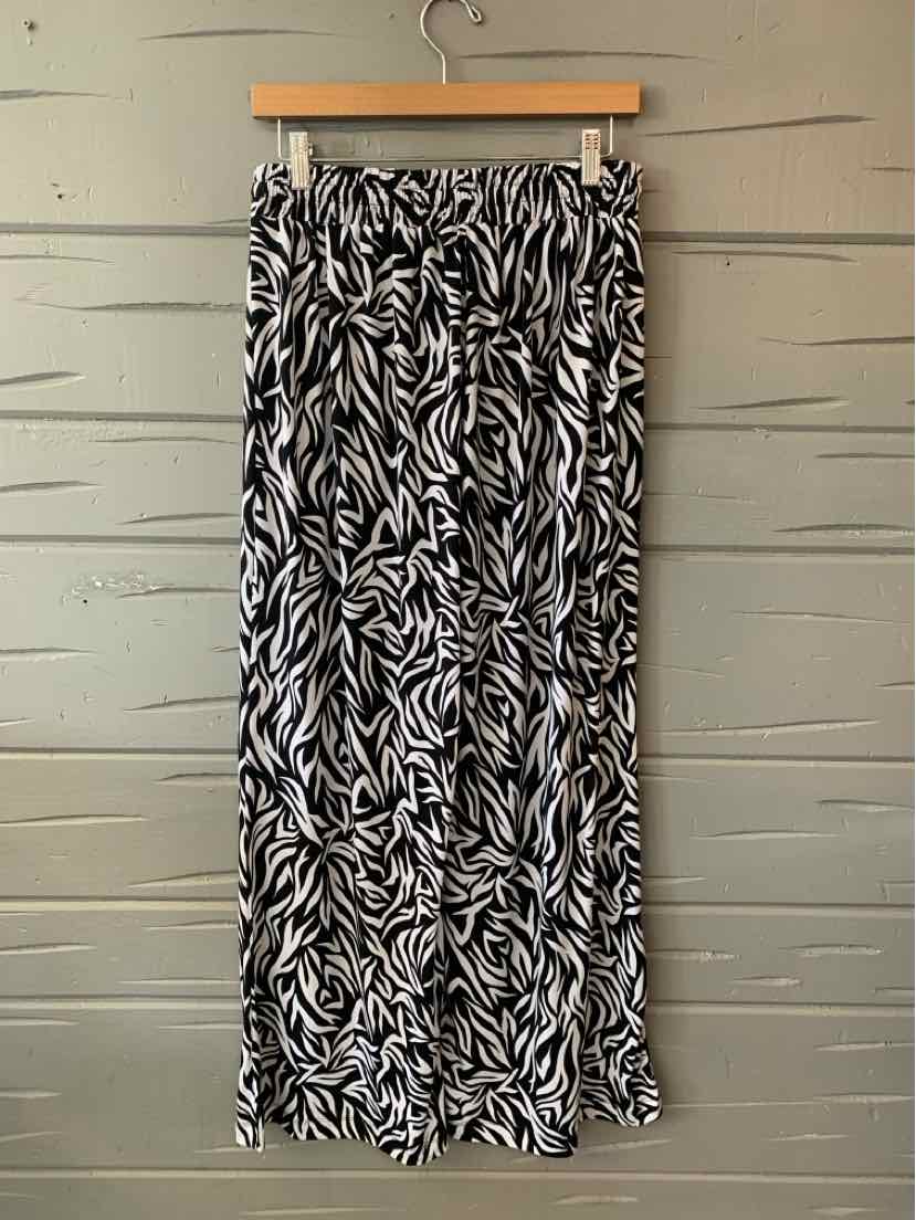 Black and white geometric patterned long skirt with elastic waistband hanging on wooden hanger.