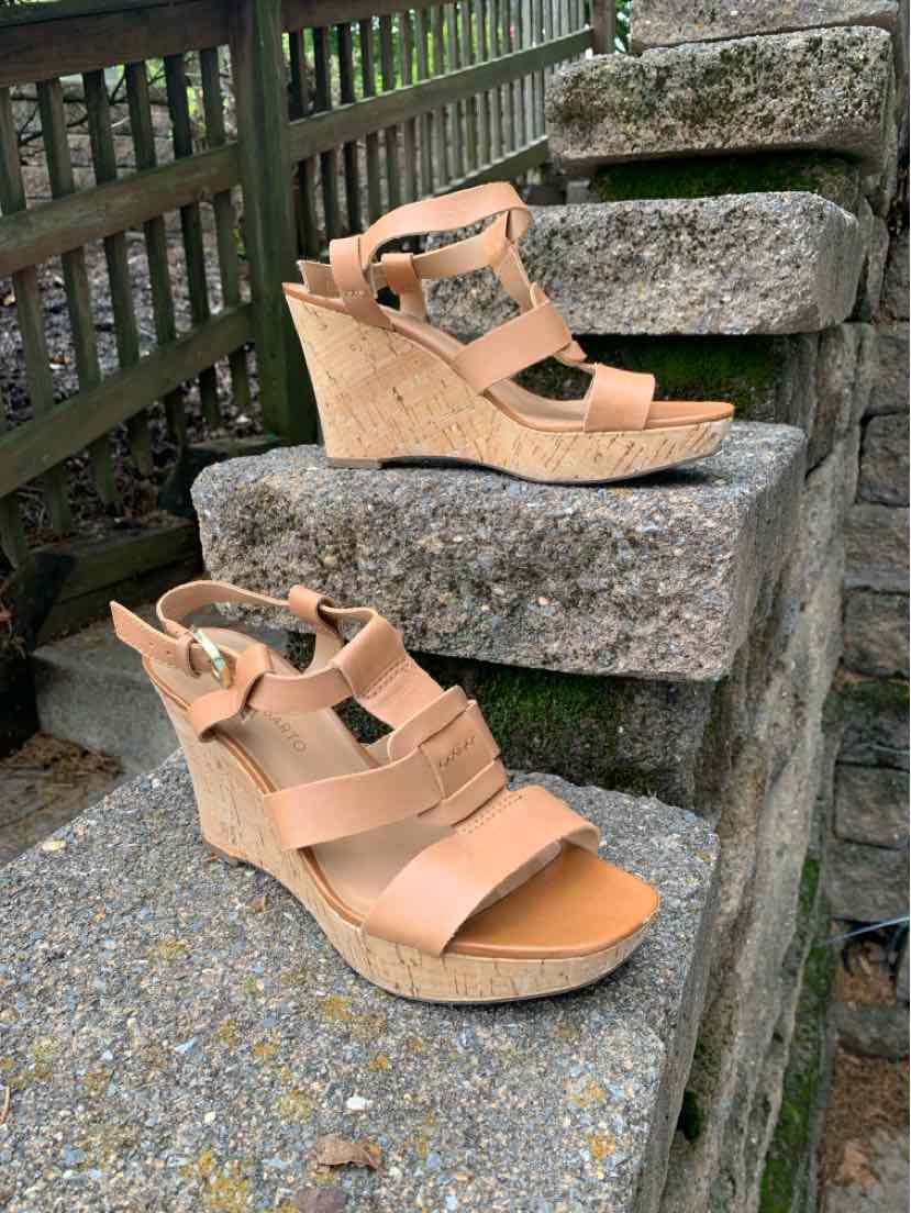 Tan wedge sandals with wide straps and adjustable ankle buckle on textured sole.