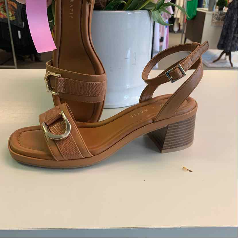 Tan leather sandal with block heel, open toe, ankle strap, and gold buckle detail.