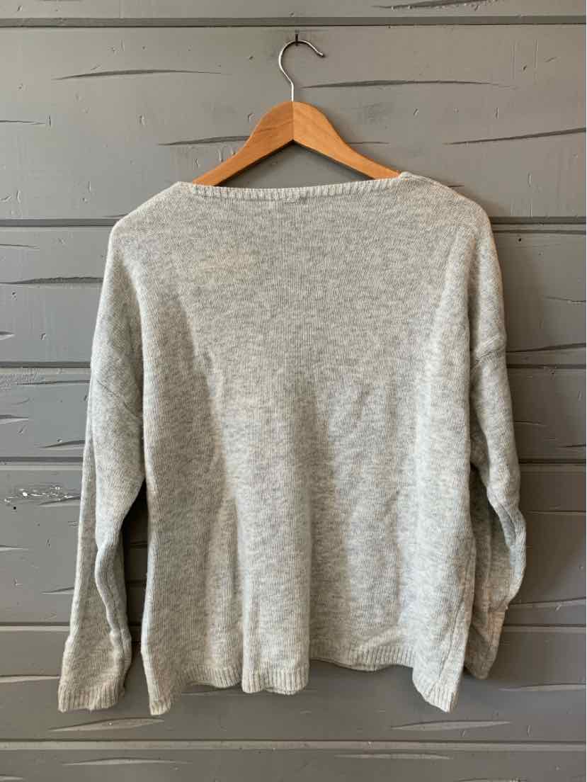 Light gray knit sweater with long sleeves and a relaxed fit hanging on a wooden hanger.